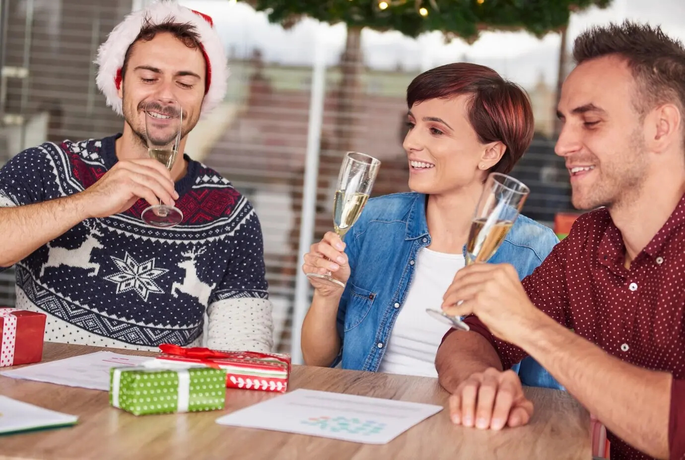 Трое молодых людей пьют шампанское в офисе.